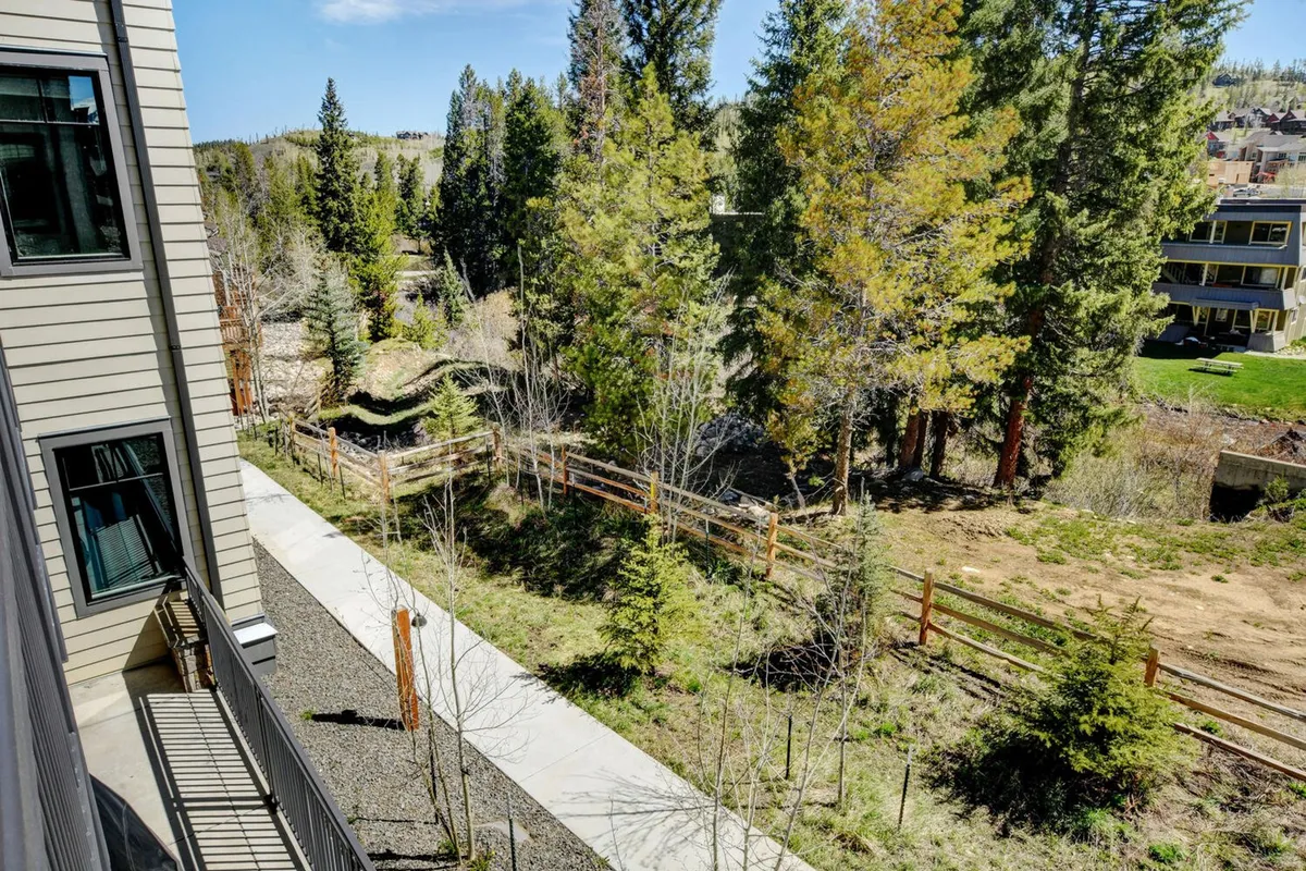 An inviting exterior scene with tall trees flanking a rustic fenced pathway, set in lush landscape. The peaceful ambiance suggests easy access to the outdoors, seasonal changes, and moments of tranquility while exploring the area.