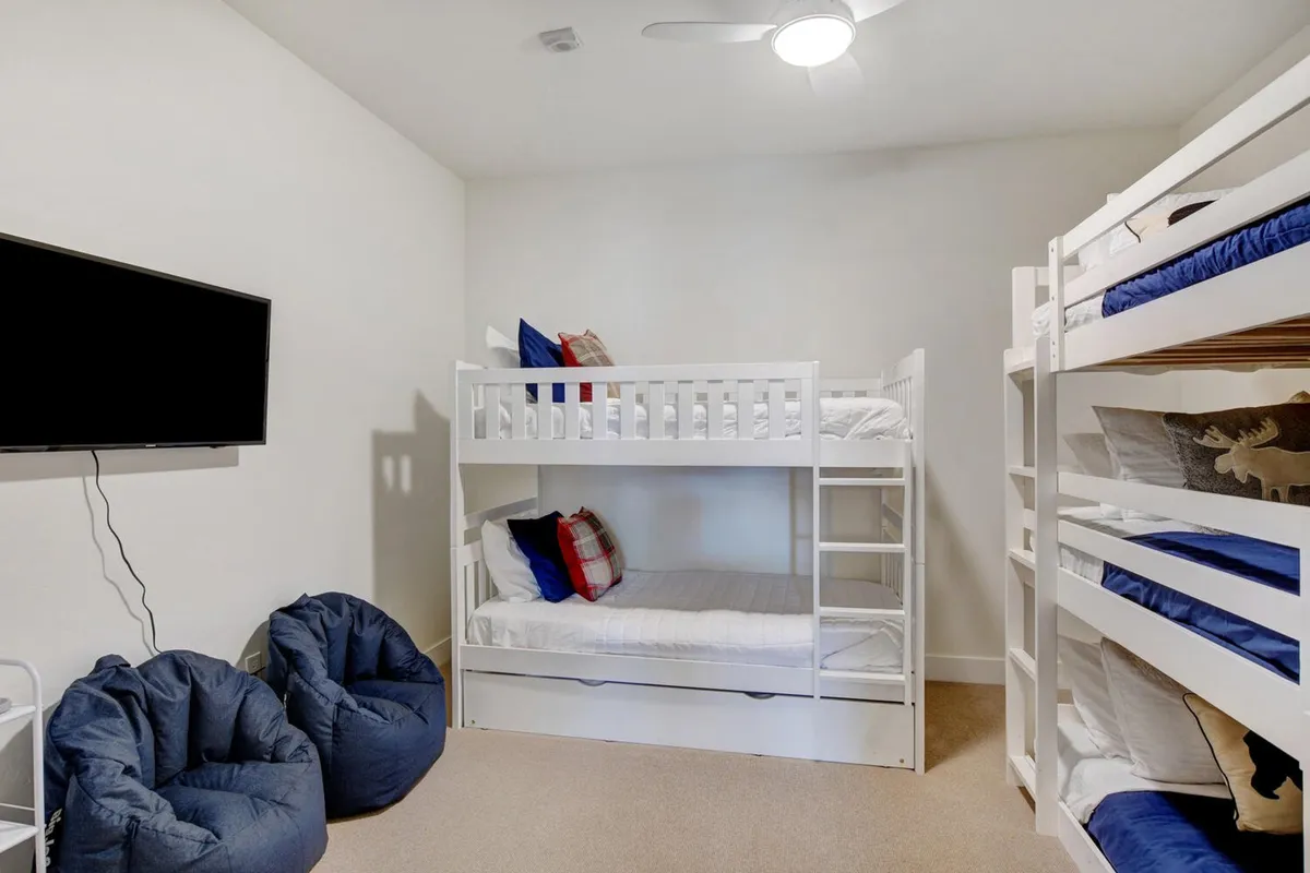 A playful bunk room outfitted with custom bunk beds, plush bean bags, and a TV, creating a joyful space for kids or teens to sleep, play, and hang out. The atmosphere is cheerful and relaxed, perfect for group or family stays.